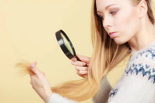 Traurige Frau blickt auf beschädigte Haarspitzen. — Stockfoto