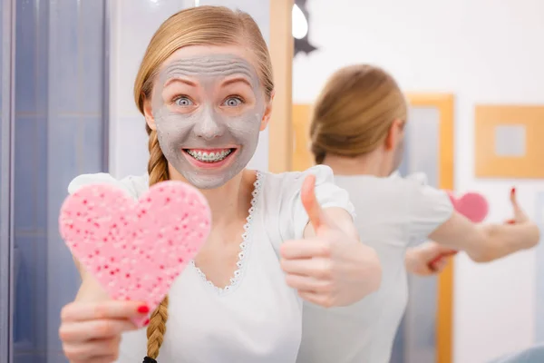 Mulher com máscara cinza segurando esponja do coração — Fotografia de Stock