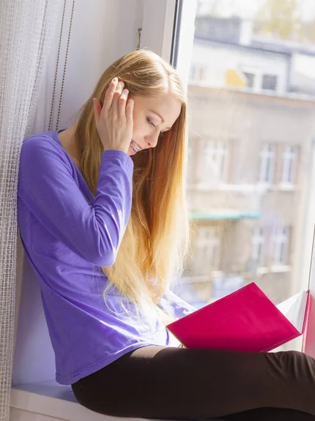 Mujer sentada en el alféizar de la ventana leyendo libro en casa — Foto de Stock