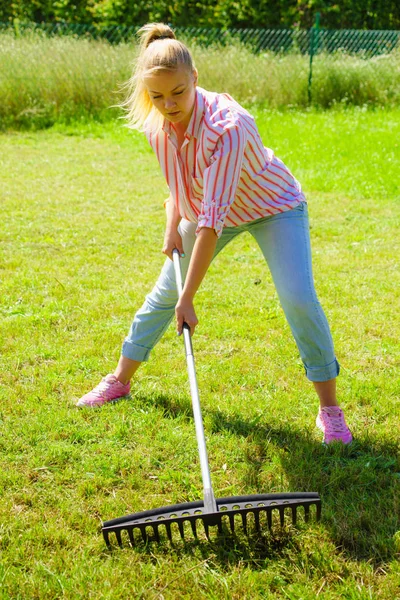 Mujer usando rastrillo para limpiar el jardín — Foto de Stock
