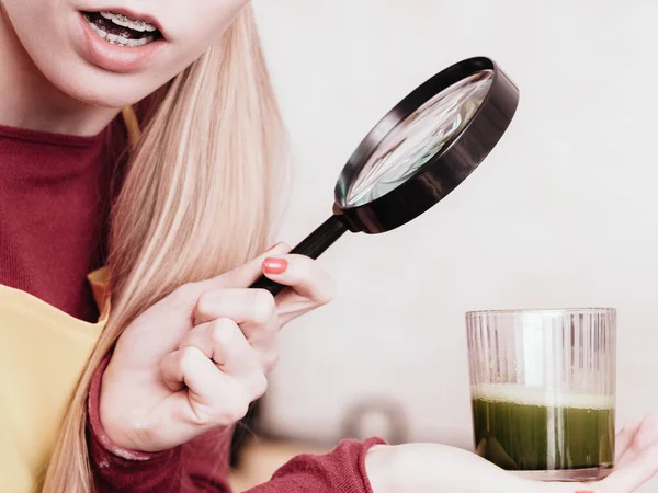 Femme regardant le jus de légumes à travers la loupe — Photo