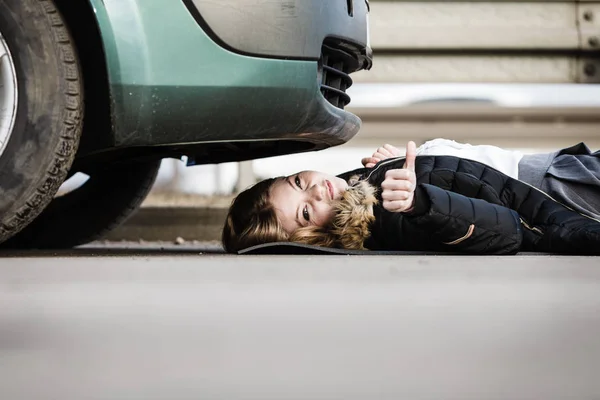 Vrouw, repareren gebroken auto liggen onder het — Stockfoto