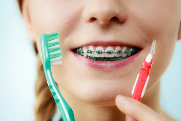 Menina com aparelho de dentes usando escova interdental e tradicional — Fotografia de Stock