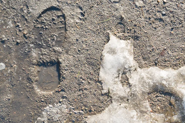 Derretimiento de nieve con huellas de zapatos humanos — Foto de Stock