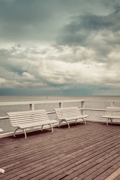 Wooden pier with white benches on sea — Stock Photo, Image