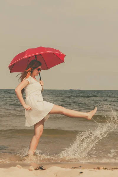 Femme rousse marchant sur la plage tenant parapluie — Photo