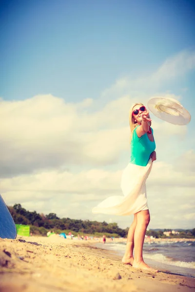 Mujer en playa lanzando sombrero de sol —  Fotos de Stock