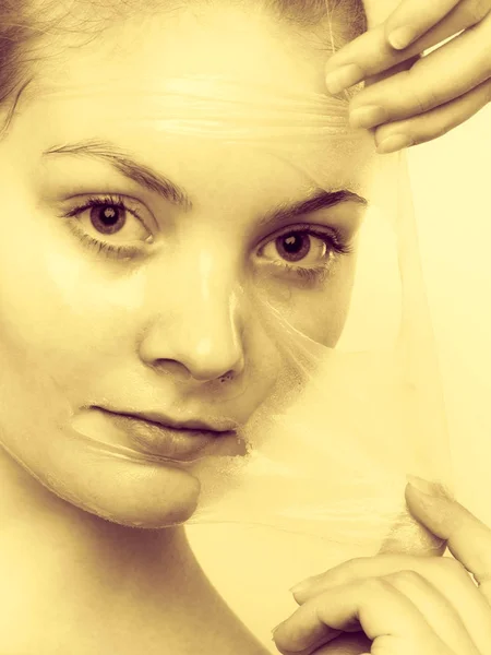 Kvinna att ta bort facial peel off mask. — Stockfoto