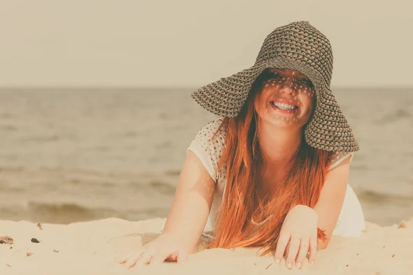 Sahilde yalan güneş şapka giyen Kızıl saçlı kadın — Stok fotoğraf