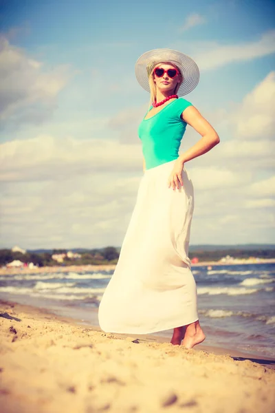 Blonde vrouw dragen jurk wandelen op strand — Stockfoto