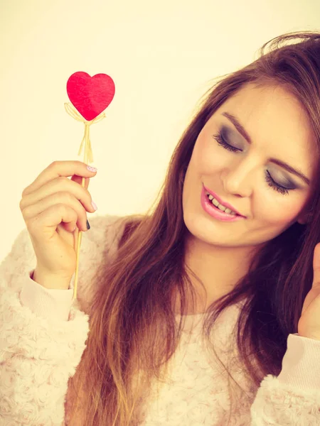 Flirty woman holding red wooden heart on stick — Stock Photo, Image