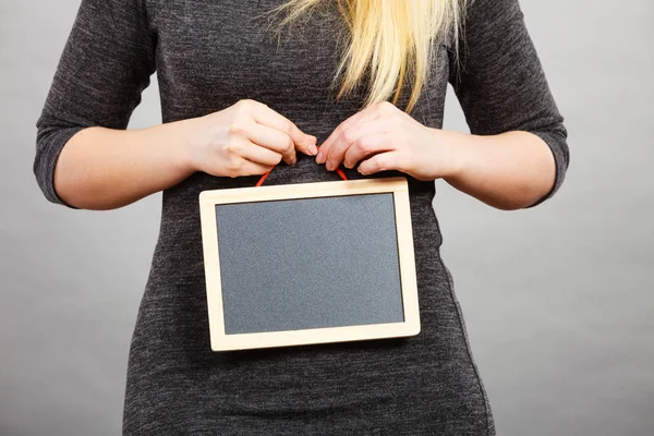 Woman holding blank black board on stomach