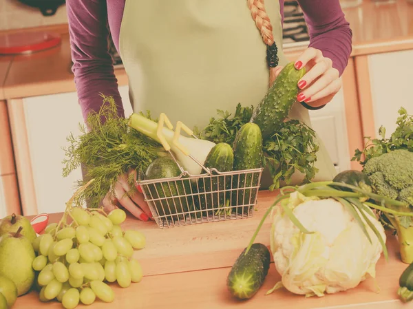 Mujer en cocina teniendo verduras sosteniendo cesta de la compra — Foto de Stock