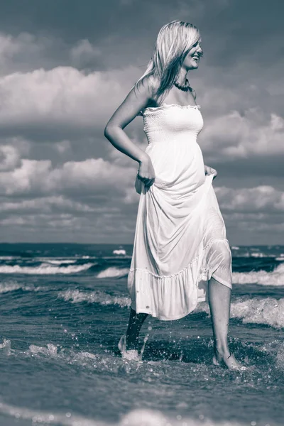 ブロンドの女性は水の中を歩くドレスを着て — ストック写真