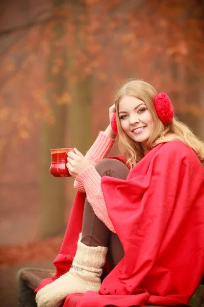 Девушка в осеннем парке наслаждается горячим напитком — стоковое фото