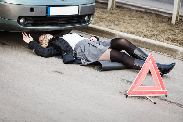 Žena, opravy rozbité auto, ležící pod ním — Stock fotografie