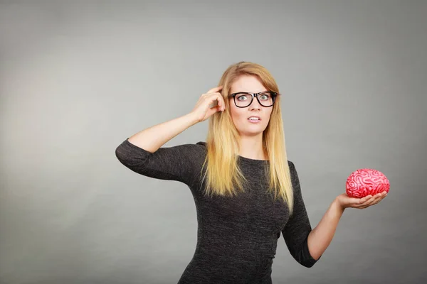 Mujer con gafas siendo confundida sosteniendo el cerebro — Foto de Stock