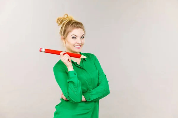 Mujer sonriente sostiene un lápiz grande en la mano — Foto de Stock
