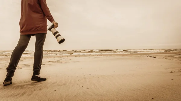 Vrouw lopend op het strand met camera — Stockfoto