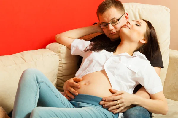 Mujer embarazada y hombre relajándose en el sofá — Foto de Stock