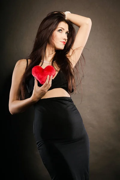 Hermosa mujer sostiene el corazón rojo en negro — Foto de Stock