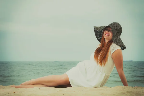 Redhead woman wearing sun hat lying on beach — Stock Photo, Image