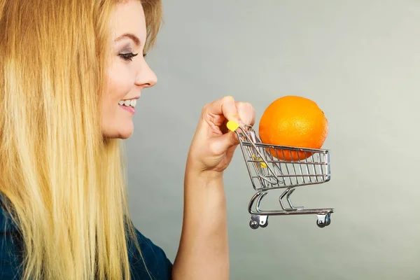 ショッピングカート内のオレンジ色を保持している女性 — ストック写真