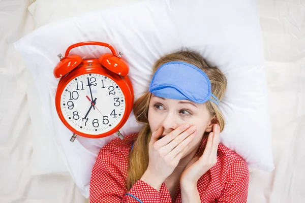 Shocked woman wearing pajamas holding clock overslept — Stock Photo, Image