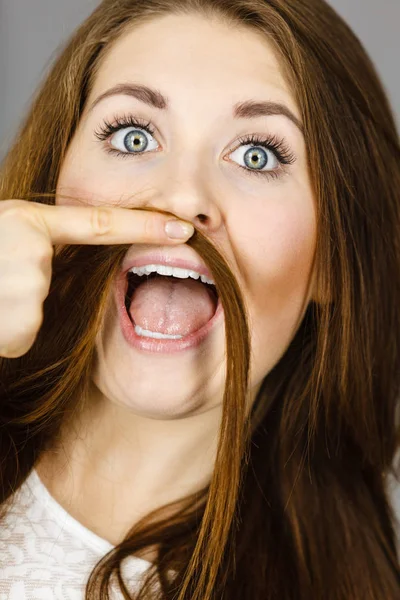 Женщина развлекается с волосами, делая усы — стоковое фото
