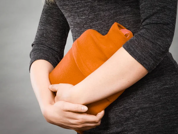 Ragazza che ha mal di stomaco, tenendo in mano la bottiglia di acqua calda — Foto Stock