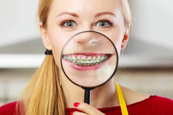 Happy woman showing her braces in magnifying glass — Stock Photo, Image