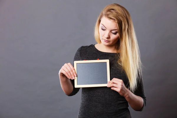 Woman holding blank black board on breast — Stock Photo, Image
