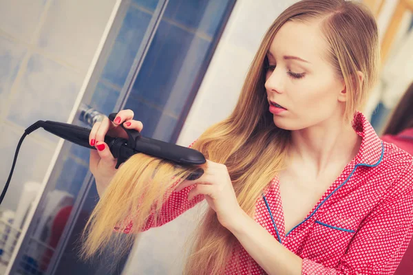 Mulher endireitando seu longo cabelo loiro — Fotografia de Stock