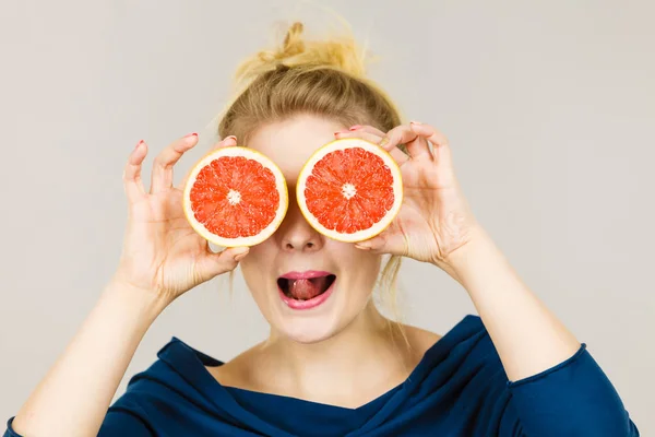 Mulher que segura a toranja de fruto metade em olhos — Fotografia de Stock