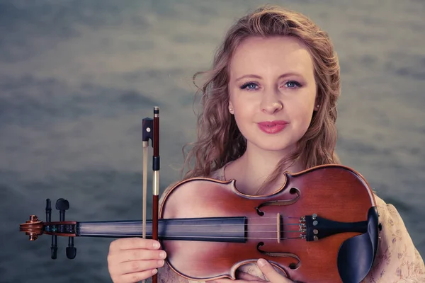 Kvinde på stranden nær havet holder violin - Stock-foto