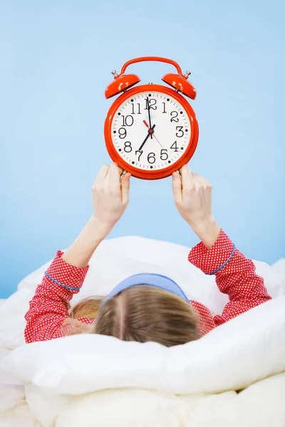 Schlafende Frau im Schlafanzug hält Uhr — Stockfoto