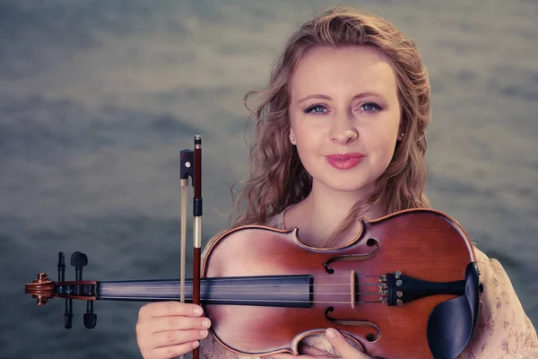 Woman on beach near sea holding violin — Stock Photo, Image