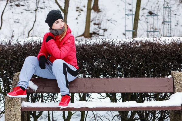 冬の間に外に座っているスポーツウェアを着ている女性 — ストック写真