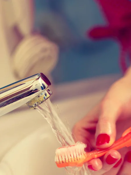 Woman cleaning her toothbrush — Stock Photo, Image