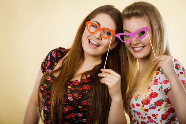 Duas mulheres felizes segurando óculos falsos no pau — Fotografia de Stock