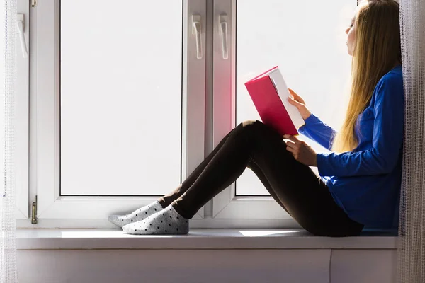 Mujer sentada en el alféizar de la ventana leyendo libro en casa —  Fotos de Stock