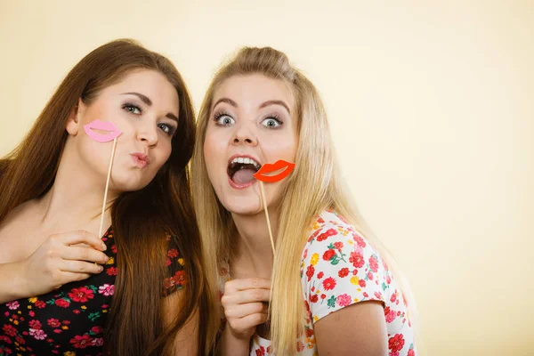 Дві щасливі жінки тримають підроблені губи на паличці — стокове фото