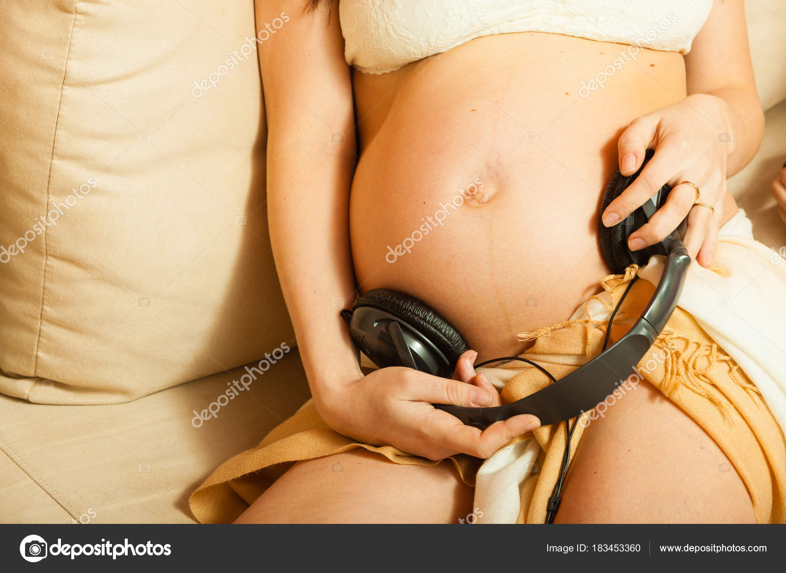 Woman with headphones on pregnant belly Stock Photo by ©Voyagerix 183453360