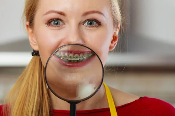 Happy woman showing her braces in magnifying glass — Stock Photo, Image