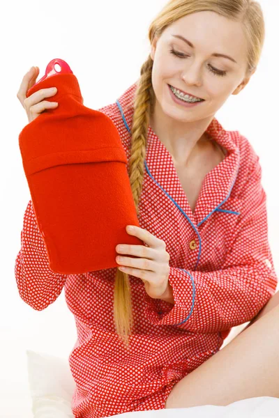 Woman holding warm red hot water bottle — Stock Photo, Image