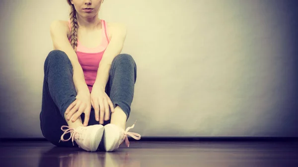 Vrouw in sportkleding zittend op grond — Stockfoto