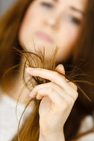 Mujer preocupada mirando sus puntas de cabello seco — Foto de Stock