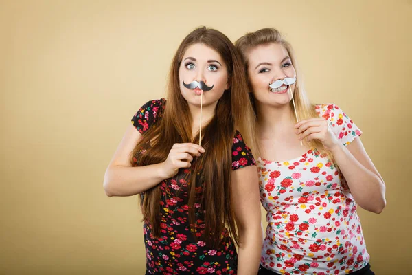 Две счастливые женщины с фальшивыми усами на палочке — стоковое фото