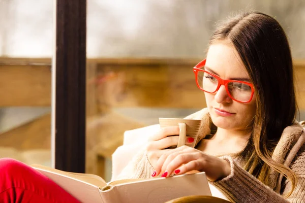 Frau sitzt auf Stuhl und liest Buch zu Hause — Stockfoto