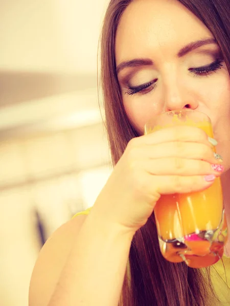 Женщина на кухне пьет свежий апельсиновый сок — стоковое фото